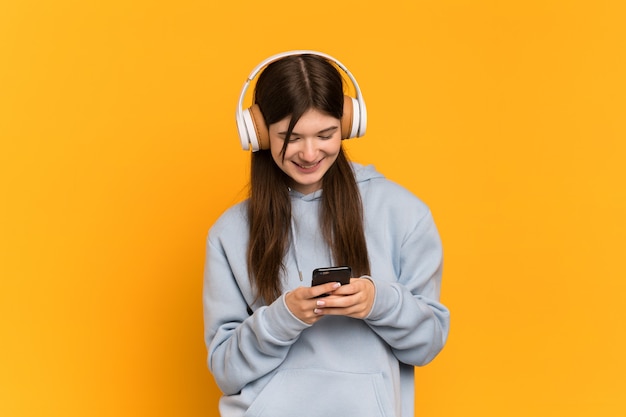 Jong meisje over geïsoleerde muziek luisteren en op zoek naar mobiel