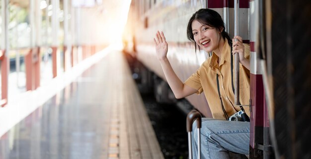 Jong meisje reizigers zwaaien met de hand zit bij de treindeur mooie reizigersvrouw stapt in de trein Reizen concept