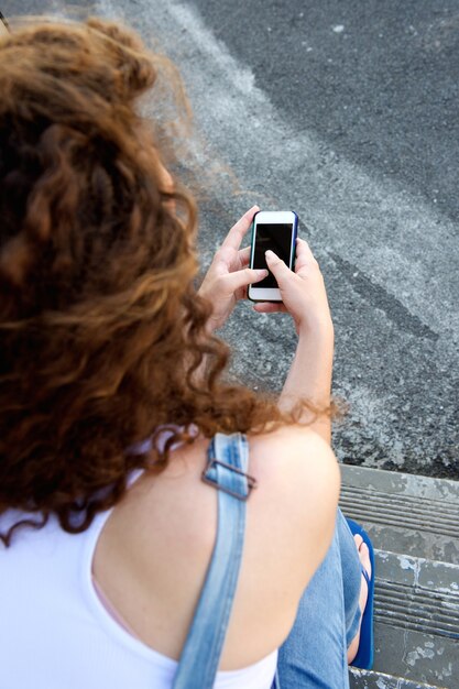 Jong meisje van achter het houden van cellphone en het texting