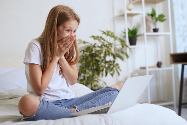 Jong meisje verheugt zich over bericht online op laptop