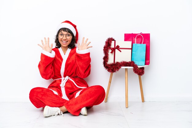 Jong meisje viert Kerstmis zittend op de vloer geïsoleerd op witte bakcground tien tellen met vingers