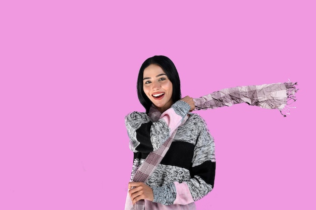 jong meisje voorste pose met een glimlach die winterkleren draagt op een roze achtergrond Indiaas Pakistaans model