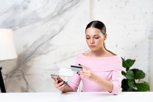 Jong meisje vrouw kijken naar creditcard betalen online in winkel met behulp van bankdienst invoeren