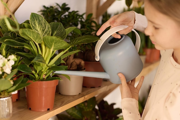 Foto jong meisje watert kamerplanten.