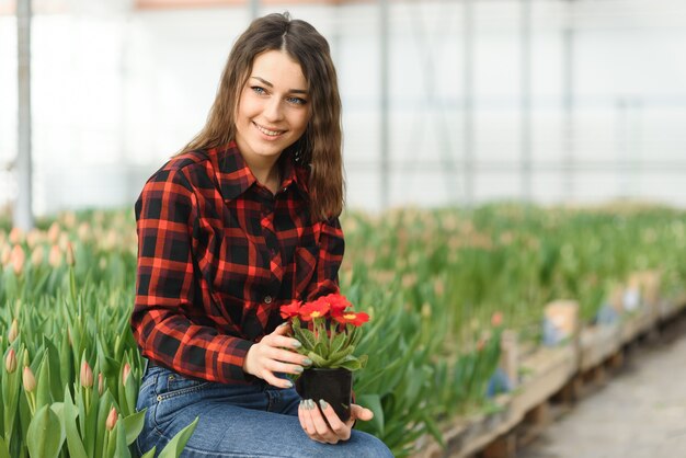 Jong meisje, werknemer met bloemen in kas