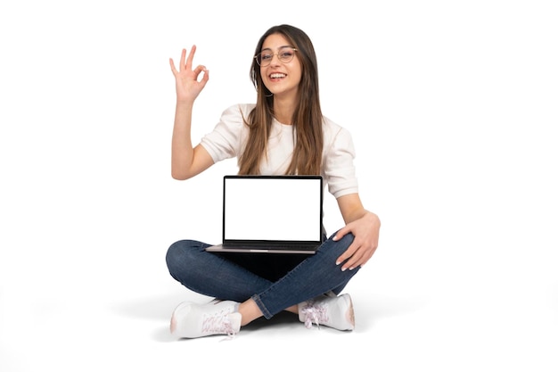 Jong meisje zittend op de grond en laptop mock omhoog houden Aanbevelende website