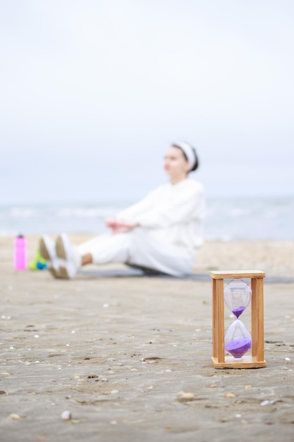 Jong meisje zittend op de grond Zandklok op de grond op het strand Foto van hoge kwaliteit