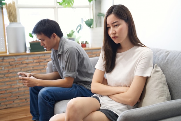 Jong meisje, zittend op de sofa voelt zich vervelen met haar vriendje