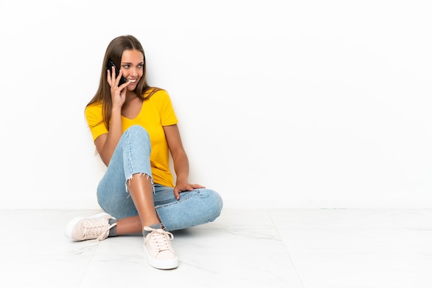 Jong meisje zittend op de vloer een gesprek met de mobiele telefoon met iemand houden