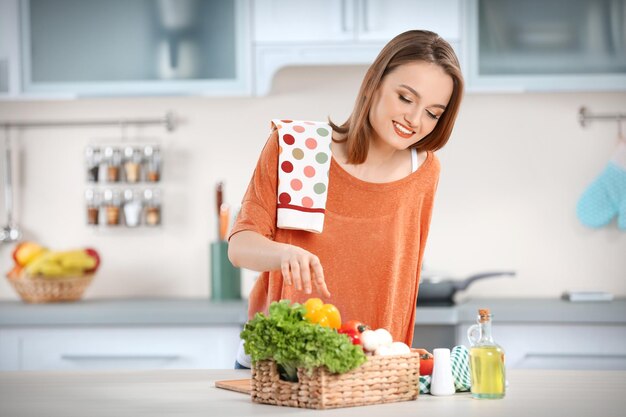 Jong met met mandje verse groenten in de keuken