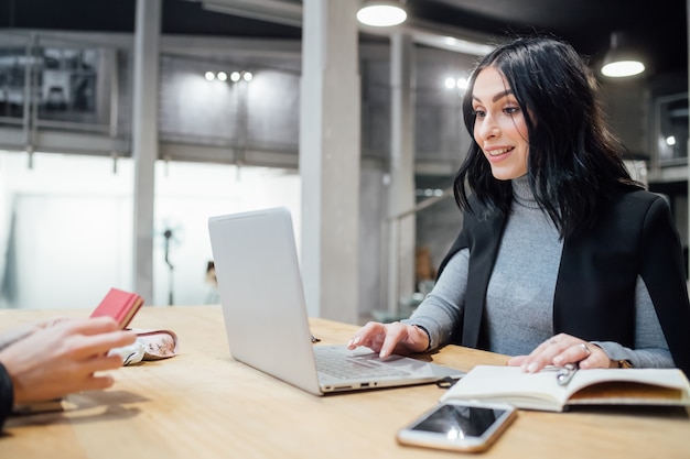 Jong mooi de zittingbureau van de vrouwen binnen gebruikend computer