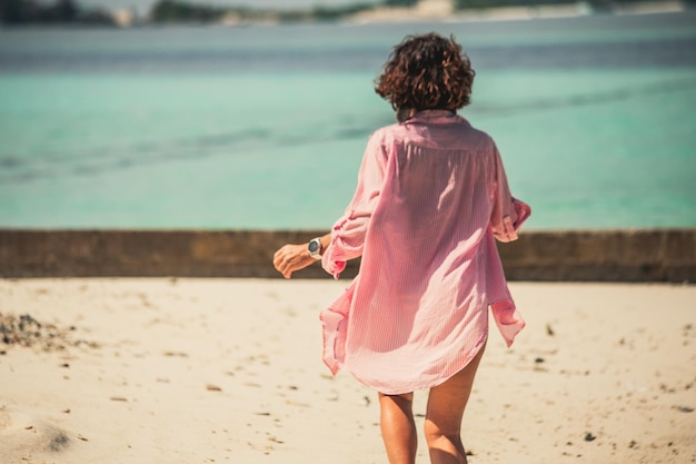 Jong mooi meisje achteraanzicht wandelen langs het strand in de malediven