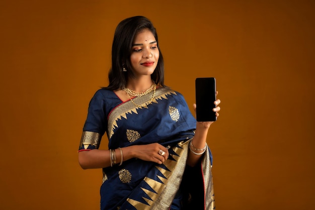 Jong mooi meisje dat een leeg scherm van smartphone of mobiel of tablettelefoon toont