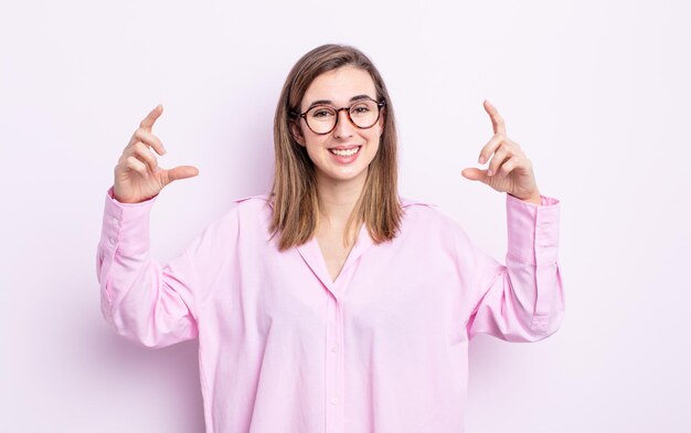 Jong mooi meisje dat haar eigen glimlach met beide handen inkadert of schetst, er positief en gelukkig uitziet, wellnessconcept