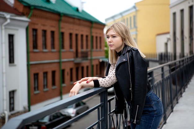 Jong mooi meisje dat zich op de brug in de stad bevindt. Blonde romantische te wachten.