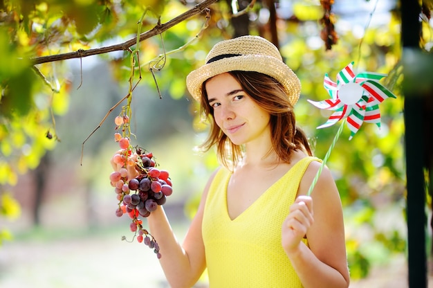 Jong mooi meisje die zachte druif in zonnige dag in Italië plukken. Gelukkige vrouwelijke landbouwer die in fruitboomgaard werken