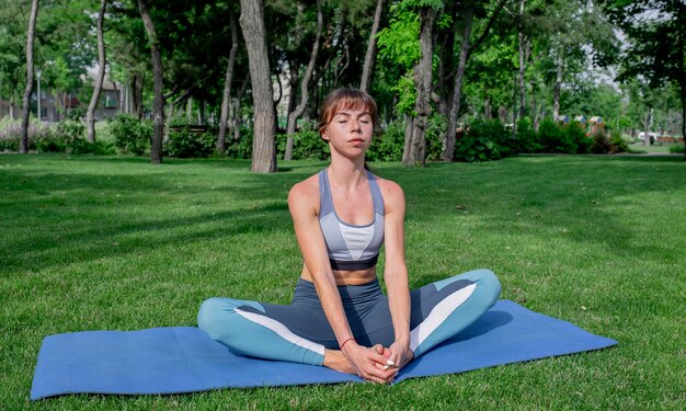 jong mooi meisje doet yoga op een groen gazon