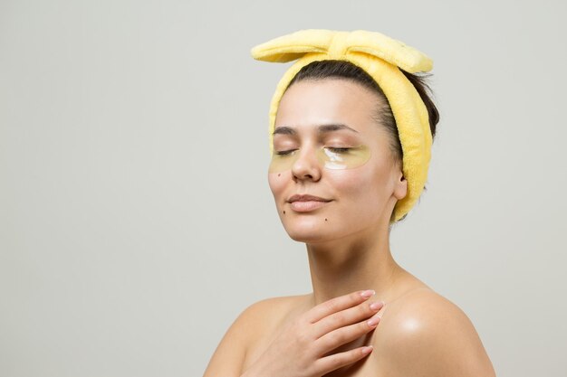 Jong mooi meisje in een witte handdoek op zijn hoofd draagt collageengelpleisters onder haar ogen Masker onder ogen behandeling gezicht