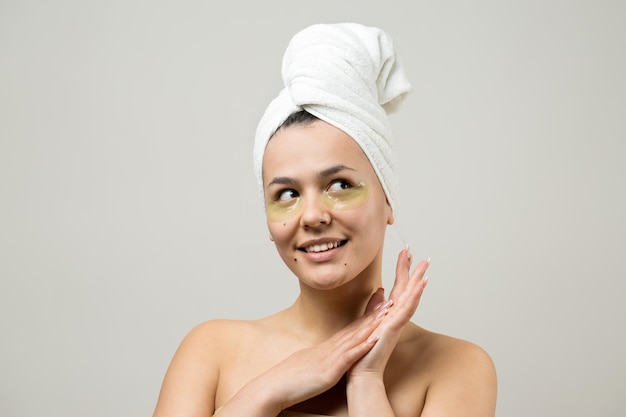 Jong mooi meisje in een witte handdoek op zijn hoofd draagt collageengelpleisters onder haar ogen Masker onder ogen behandeling gezicht