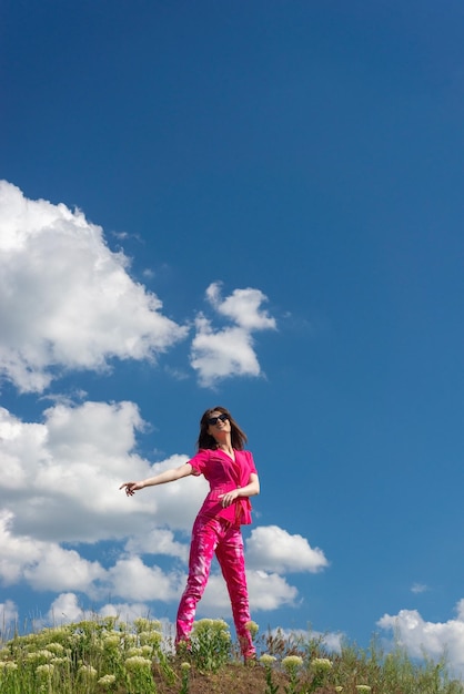 Jong mooi meisje in roze op een achtergrond van wolken in de zomer blauwe lucht