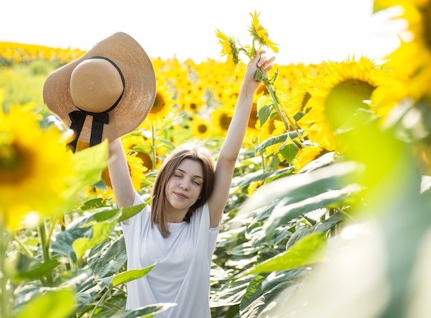 Jong mooi meisje loopt in de zomer in een veld met bloeiende zonnebloemen