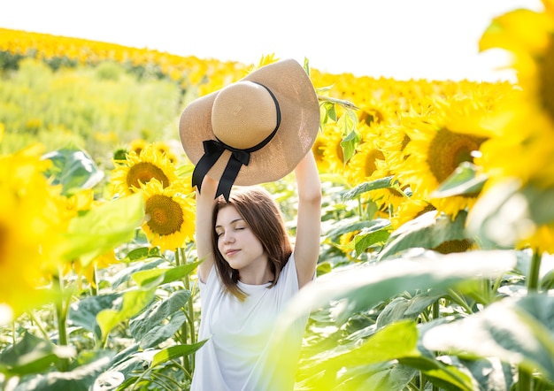 Jong mooi meisje loopt in de zomer in een veld met bloeiende zonnebloemen