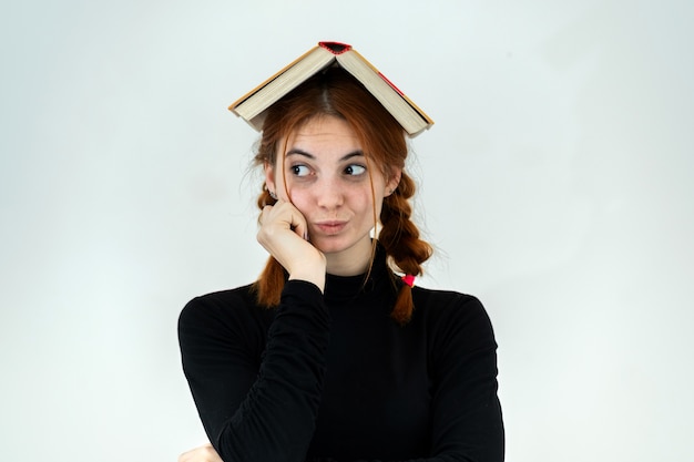 Jong mooi meisje met een open boek op haar hoofd. Lezen en onderwijs concept.