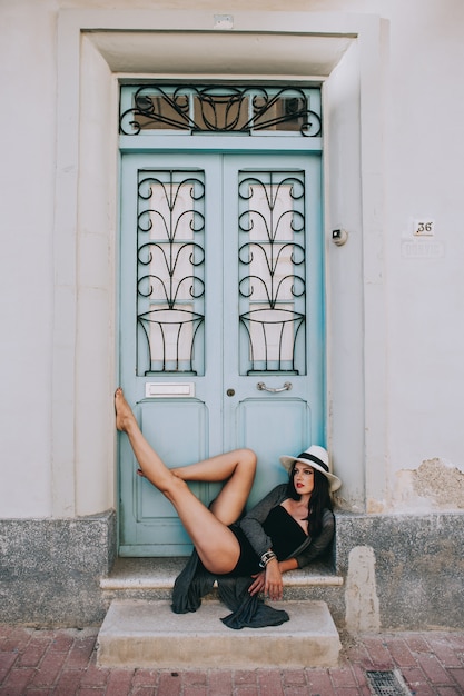 jong mooi meisje met hoed poseren tegen de achtergrond van een antieke deur