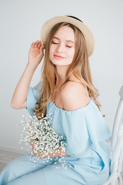 Jong mooi meisje met lang haar en hoed poseren met een boeket witte bloemen. tonen.