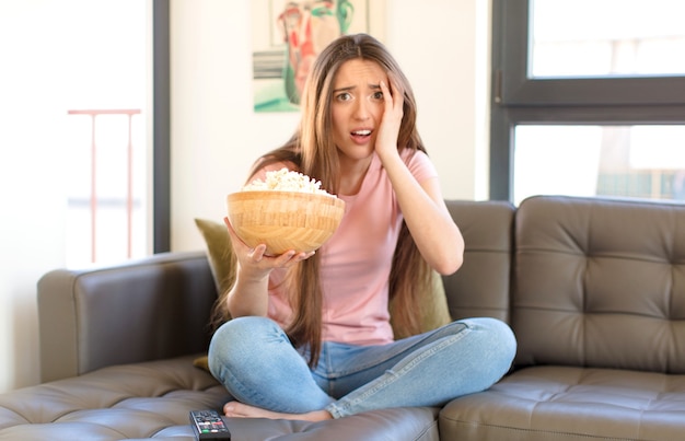 Jong mooi meisje met popcorns kijken naar een film thuis