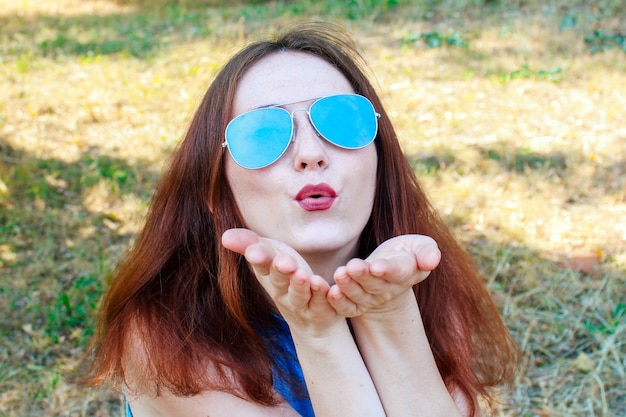 Jong mooi meisje met rood haar kijken naar de camera, het dragen van een zonnebril.