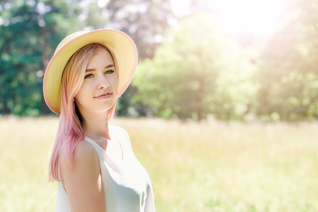 Jong mooi meisje met roze haar in de zomerhoed op de open plek