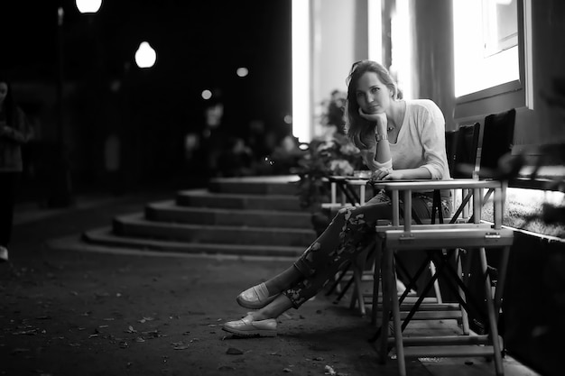 Jong mooi meisje zit 's nachts in een straatcafé