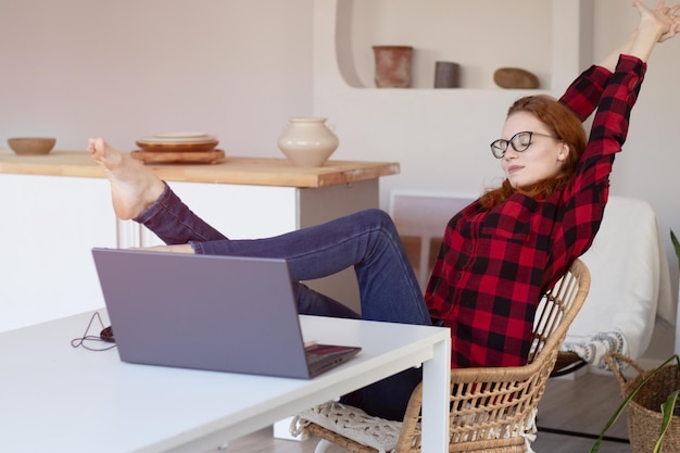 Jong mooi roodharig meisje praten met behulp van een computer thuis in de keuken