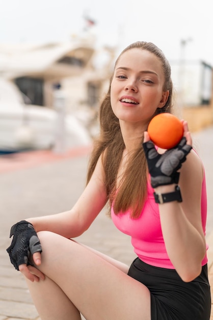 Jong mooi sportmeisje dat in openlucht een sinaasappel houdt