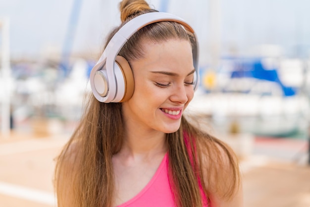 Jong mooi sportmeisje dat in openlucht muziek luistert