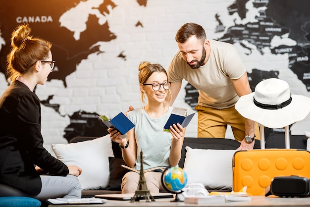 Jong mooi stel zit met manager op het kantoor van het reisbureau en bereidt zich voor op een zomervakantie