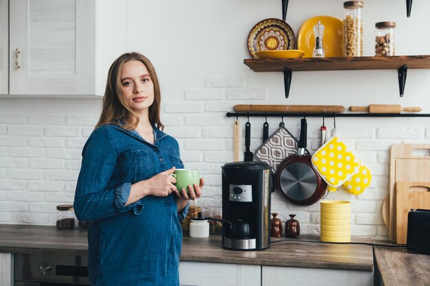 Jong mooi zwanger meisje werkt thuis in zelfisolatie modus in quarantaine en neemt een pauze om uit te rusten met koffie