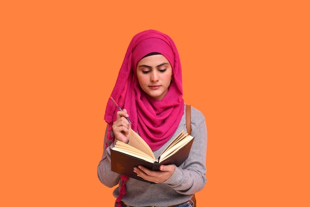 jong moslimmeisje die hijab hangende zak draagt en boek Indisch Pakistaans model houdt