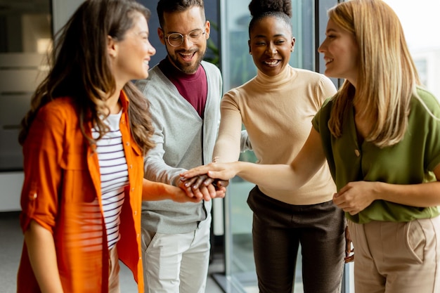 Foto jong multi-etnisch startup-team houdt elkaar bij de hand in het moderne kantoor