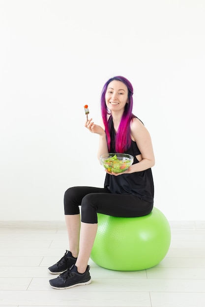 Jong niet-geïdentificeerd fitnessblogger-meisje met groentesalade en meetlint Concept van sportieve levensstijl en goede voeding
