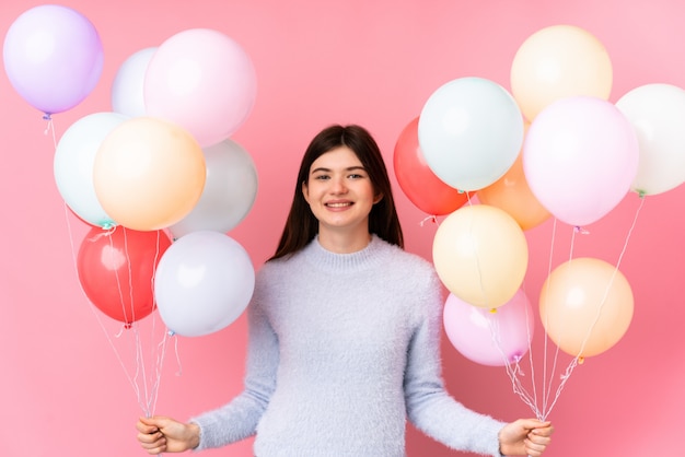 Jong Oekraïens tienermeisje dat veel ballons over roze muur houdt