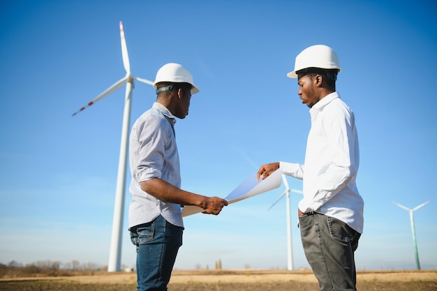 Jong onderhoudsingenieursteam dat in windturbinepark werkt bij zonsondergang stock foto