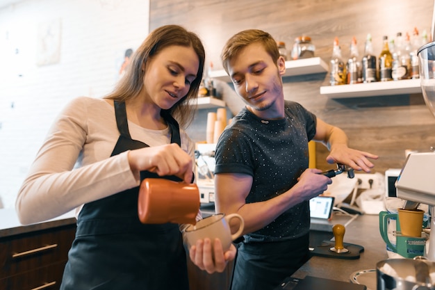 Jong paar dat dichtbij koffiemachines werkt, die dranken maakt