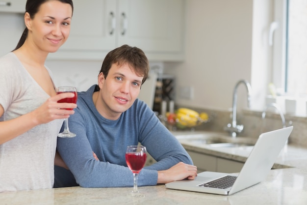 Jong paar dat laptop gebruikt die rode wijn drinkt