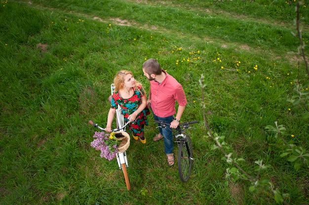 Jong paar dat met fietsen elkaar tegen de achtergrond van vers groen gras bekijkt