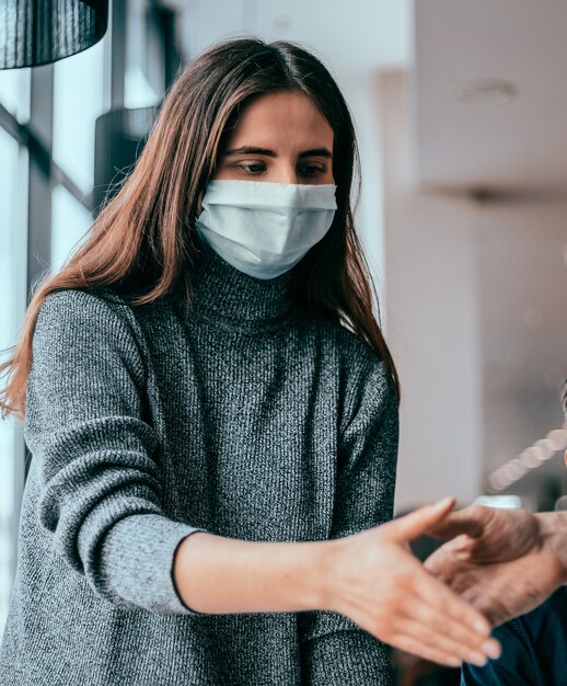 Jong personeel met beschermende maskers die elkaar de hand schudden.