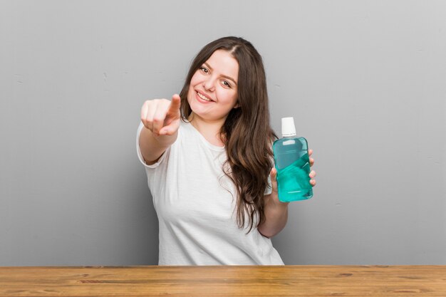 Jong plus grootte curvy vrouw met een mondwater vrolijke glimlach wijzend naar de voorkant.