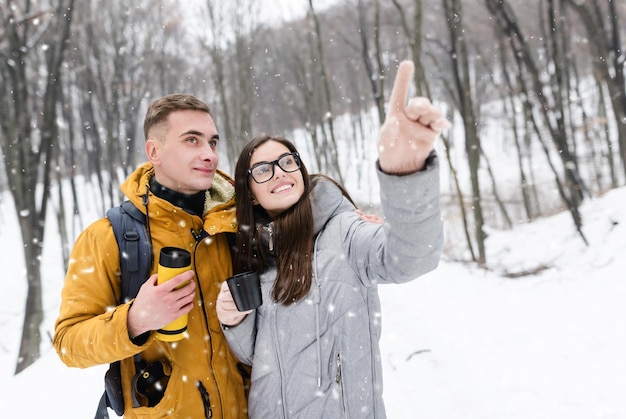 Jong romantisch stel dat thee drinkt en de sneeuwlandschappen bewondert