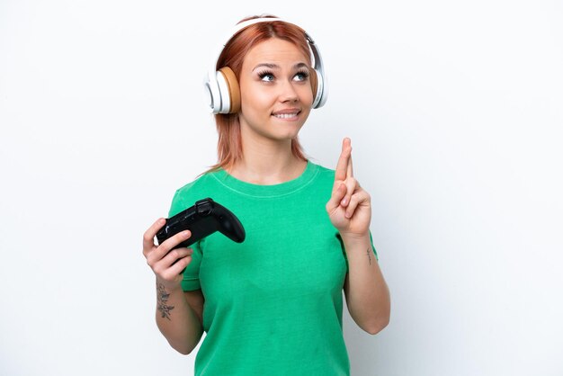 Jong Russisch meisje speelt met een videogamecontroller geïsoleerd op een witte achtergrond met vingers die elkaar kruisen en het beste wensen